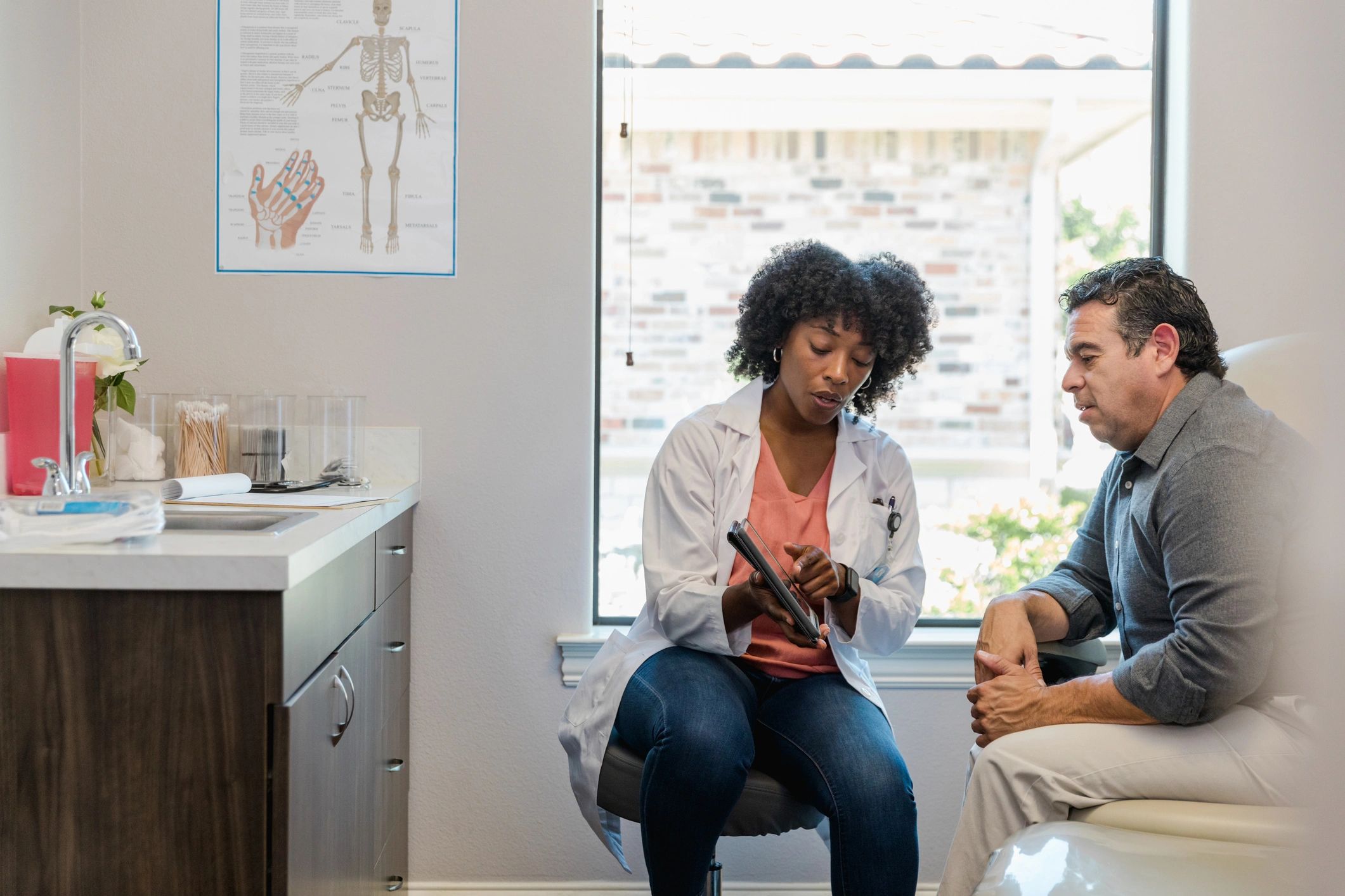 Doctor reviewing information with a patient using a tablet in a clinic office.