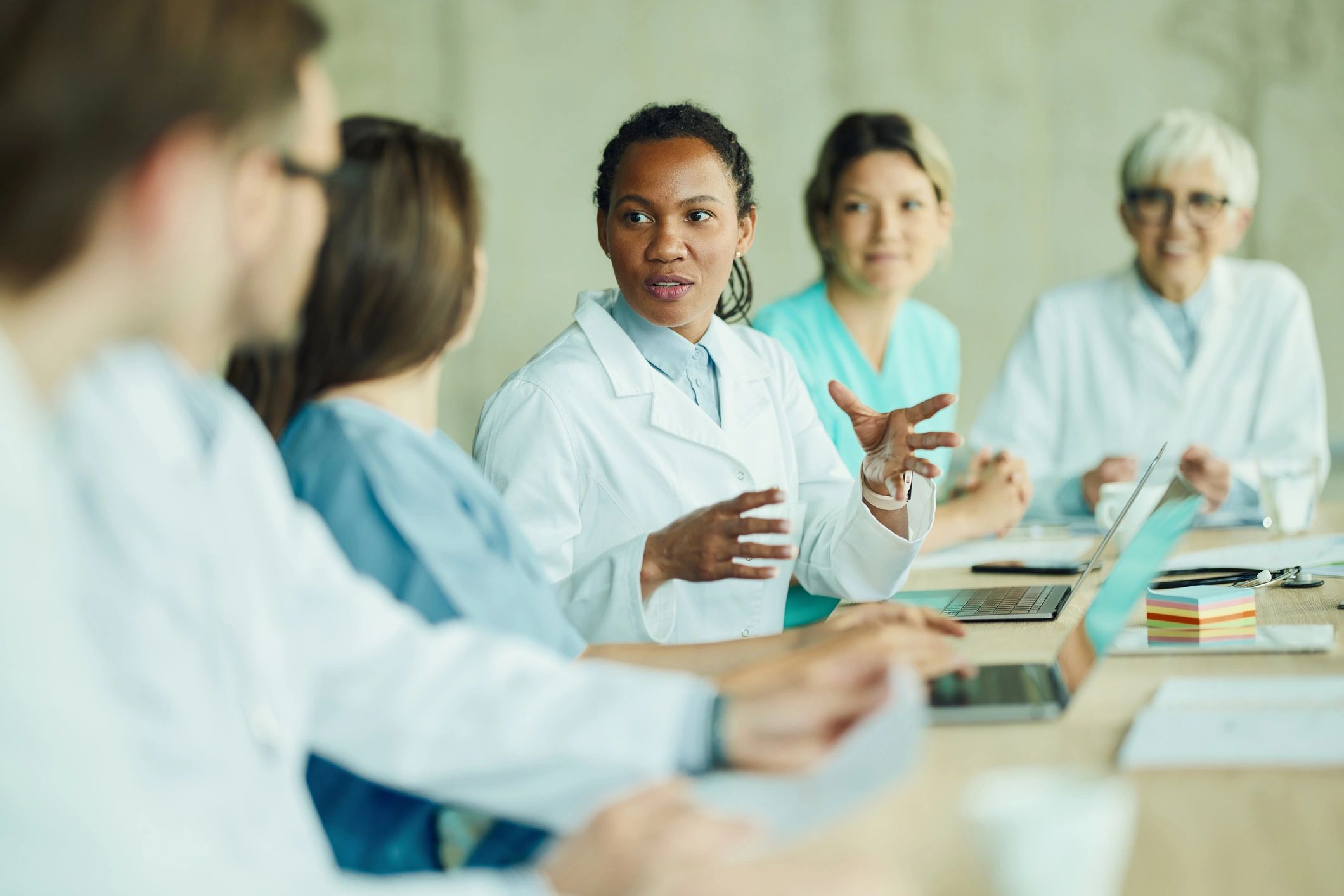 Healthcare team meeting in a hospital setting with laptops and notes.